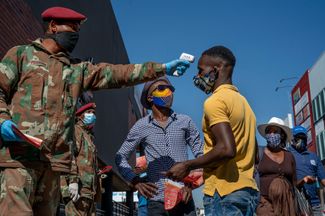 Военнослужащий проверяет температуру людей на стоянке маршрутных такси в Йоханнесбурге, 20 мая 2020 года