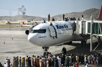 Жители Афганистана на летном поле в аэропорту Кабула пытаются покинуть страну после возвращения талибов. 16 августа 2021 года 