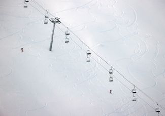 Лыжники поднимаются вдоль закрытой канатной дороги на курорте Порт-дю-Солей. Курорт расположен на территории Франции и Швейцарии. Декабрь 2020 года