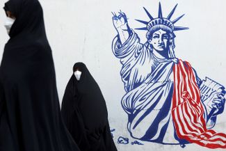 Демонстранты на фоне антиамериканского мурала на стене бывшего посольства США в Тегеране