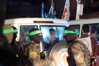 Боевики ХАМАС и «Исламского джихада» передают заложников сотрудникам Красного Креста, которые вывозят освобожденных израильтян из сектора Газа через контрольно-пропускной пункт Рафах на границе с Египтом. 28 ноября 2023 года