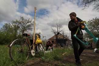 Жители Малотарановки выносят уцелевшие вещи из разрушенного российской ракетой частного жилого дома
