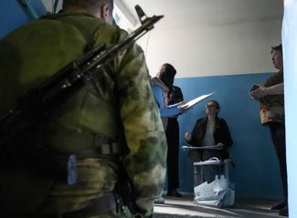 Жители Донецкой области, члены избирательной комиссии и военные с оружием на участке, где проходит «референдум о присоединении к России»