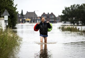 Житель городка Арсен на севере нидерландской провинции Лимбург идет по затопленным улицам. 17 июля 2021 года
