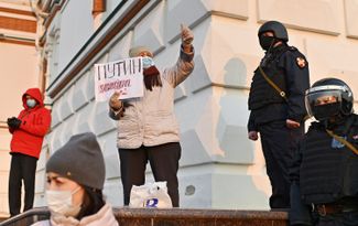 A protesters with a sign that reads “Putin is a killer”  