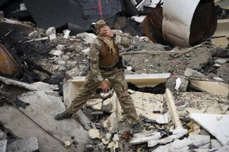 Украинский военный осматривает руины спорткомплекса