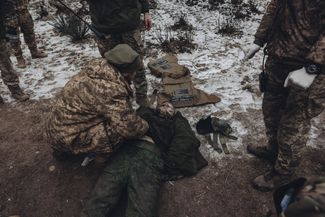 Украинские военные досматривают связанного российского пленного