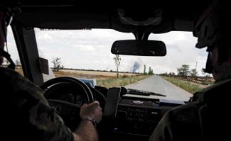 Украинские военные едут на машине недалеко от Николаева. На горизонте — дым от обстрелов.