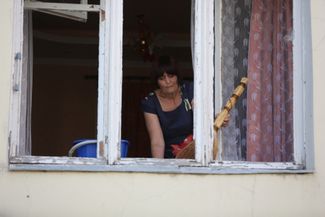 Женщина смотрит в окно в пострадавшем жилом квартале Донецка. Под обстрел в городе попали здание администрации самопровозглашенной ДНР, гостиница «Централь», где останавливаются журналисты, и многоквартирный дом