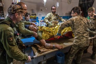 Военные медики готовят раненого украинского солдата к транспортировке в прифронтовом полевом госпитале под Попасной