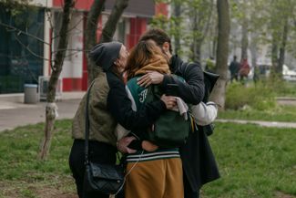 Люди обнимаются после того, как смогли покинуть многоэтажный дом в Одессе, который подвергся ракетному обстрелу с российской стороны