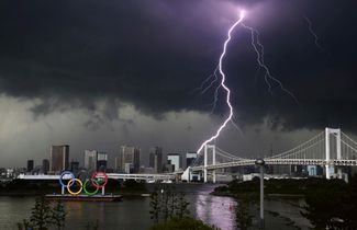 Символ Олимпиады на фоне грозы в Токио, 11 июля 2021 года.