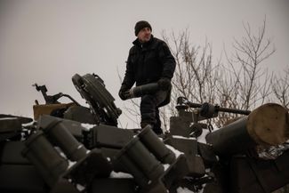 Боец ВСУ с танковым снарядом в руках стоит на танке Т-64