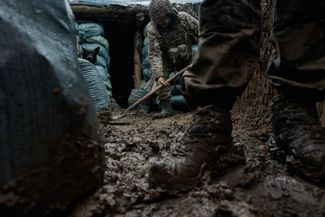 Солдат ВСУ убирает грязь из траншеи