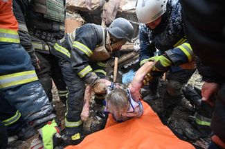 Спасатели и полицейский помогают выбраться из-под завалов жительнице Змиева Харьковской области, пострадавшей в результате российского удара