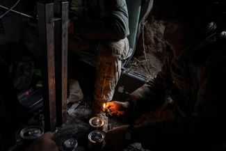 Украинский военный зажигает свечи, чтобы согреться в окопе. 20 февраля 2024 года. 