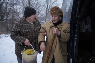 Местная жительница помогает соседке во время эвакуации из города. С начала российского вторжения в Украину Часов Яр регулярно подвергается обстрелам