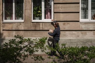 Мужчина, который разносит хлеб, стучит в окно дома в городе Лиман Краматорского района Донецкой области. Город находится под постоянными обстрелами<br>