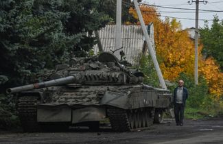 Местный житель рядом с подбитым российским танком Т-72. 