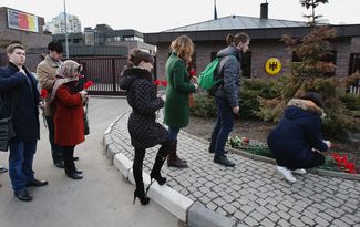 Люди возлагают цветы у немецкого посольства в Москве