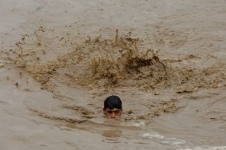 Мужчина пытается преодолеть поток в округе Чарсадда