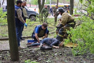 Сотрудники скорой помощи и МЧС у тела женщины, погибшей в результате обстрела Донецка