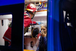 Раненый житель Винницы в машине скорой помощи возле многоквартирного дома, поврежденного ударом российских беспилотников, 25 октября 2026 года