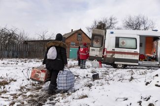 Волонтеры украинского Красного креста помогают перенести вещи эвакуируемых местных жителей.