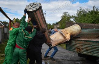 Коммунальные рабочие загружают обломки ракеты в грузовик после ночной атаки на Краматорск