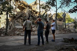 Жители Харькова смотрят на разрушенное в результате ракетного удара здание. По данным проекта «Беларускі Гаюн», российские самолеты обстреляли Украину с территории Беларуси