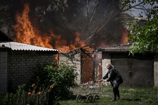 Жительница Лисичанска у горящего гаража. Российские военные ведут наступление на город.