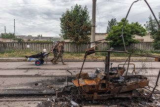 Members of the White Angel special police unit, which works to evacuate residents of front-line areas, assist a Drozkovka resident. June 13, 2026