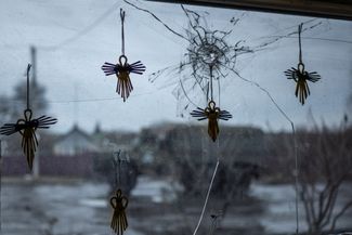 Фигурки ангелов на разбитой шрапнелью витрине продуктового магазина в одном из населенных пунктов Харьковской области (каком именно — не уточняется)