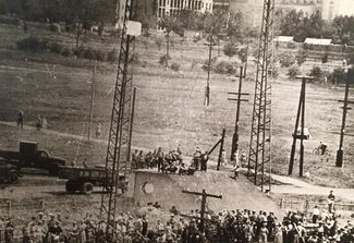 The first day of protests: workers block the railway and hang from an electrical tower a banner reading, “Meat, butter, and higher pay!” June 1, 1962. Image displayed at the Novocherkassk Memorial Museum.