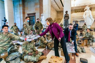 Конгрессмен и республиканка Вики Хартцлер и член парламента Майкл Вальц раздают пиццу бойцам Национальной гвардии в Центре посетителей Капитолия. 13 января 2021 года