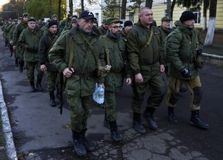 Мобилизованные россияне, которые отправятся на войну в Украине, идут по улице в Москве