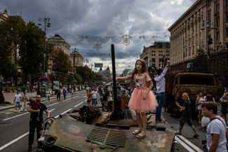 Девочка фотографируется на подбитой бронемашине на выставке захваченной и уничтоженной российской техники на Крещатике в Киеве