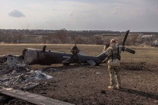 Украинские солдаты фотографируются рядом со сбитым российским вертолетом в селе Малая Рогань под Харьковом, которое вернулось под контроль Украины