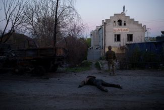 Украинский военный стоит рядом с телом российского солдата 