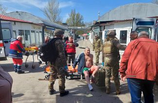 Украинские военные и врачи помогают раненому мужчине