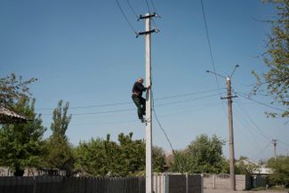 Житель Лисичанска Луганской области взбирается на столб, чтобы заново подключить электрический кабель. В городе уже 12 дней нет электричества<br>