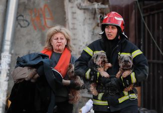 Спасатель несет двух собак раненой киевлянки