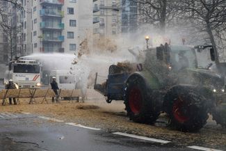 Трактор засыпает сеном бельгийских бойцов спецназа во время акции протеста в Брюсселе. 26 февраля 2024 года