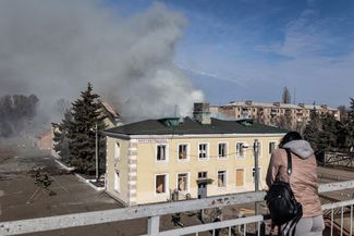 Жительница Константиновки смотрит на одно из поврежденных российской ракетой зданий