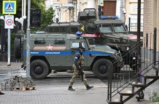 Боец ЧВК Вагнера патрулирует улицу возле штаба Южного военного округа в Ростове-на-Дону. 24 июня 2023 года