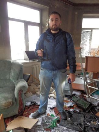 Sergei Babinets holds his Front Line Defenders Award in the burnt office of lawyers from the Committee Against Torture Joint Mobile Group, Grozny, December 14, 2014