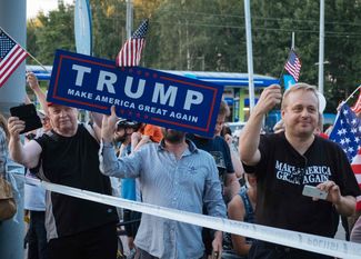 Сторонники Трампа с американскими флагами встречают кортеж президента США в Хельсинки, 15 июля 2018 года<br>