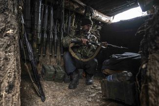 Украинский военный проверяет оружие в окопе, который расположен на линии фронта под Угледаром