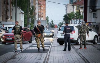 Люди в форме без опознавательных знаков и сотрудник милиции перекрывают одну из улиц в Донецке, 12 июня 2015 года