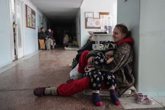 A woman with a child cries in the corridor of a hospital in Mariupol. Her second child died during the shelling of the city.